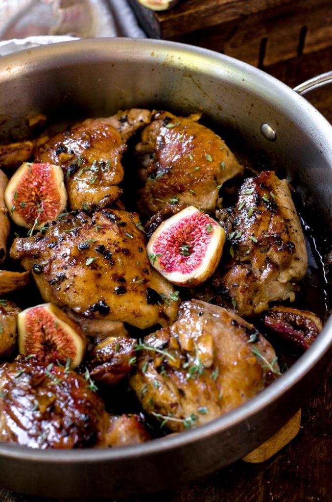 Cooked chicken thighs in a pan with fresh halved figs between them.