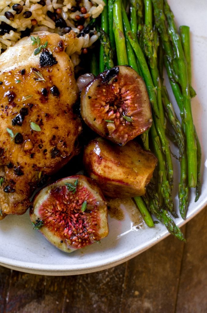 Close up of cooked figs next to chicken and asparagus.