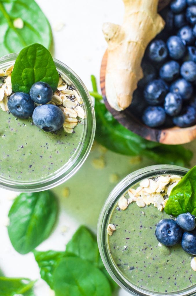 Overhead view of two green smoothies next to ingredients.