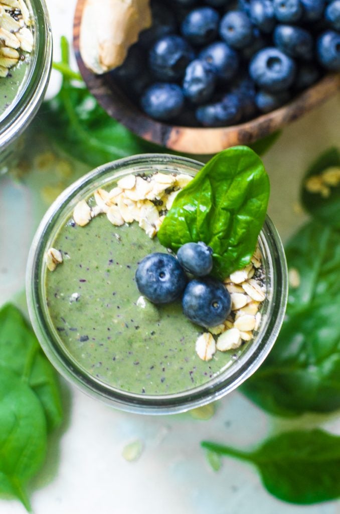 Overhead view of blueberries on top of a green smoothie.