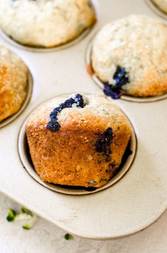 A blueberry muffin turned sideways in a muffin pan.