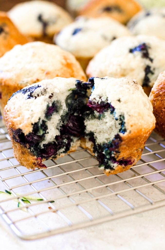 A blueberry muffin pulled open on a cooling rack.