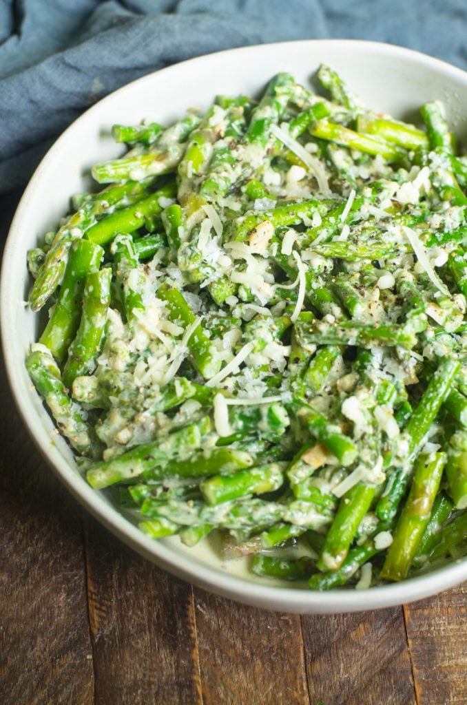 A bowl of creamed asparagus with sprinkled parmesan on top.