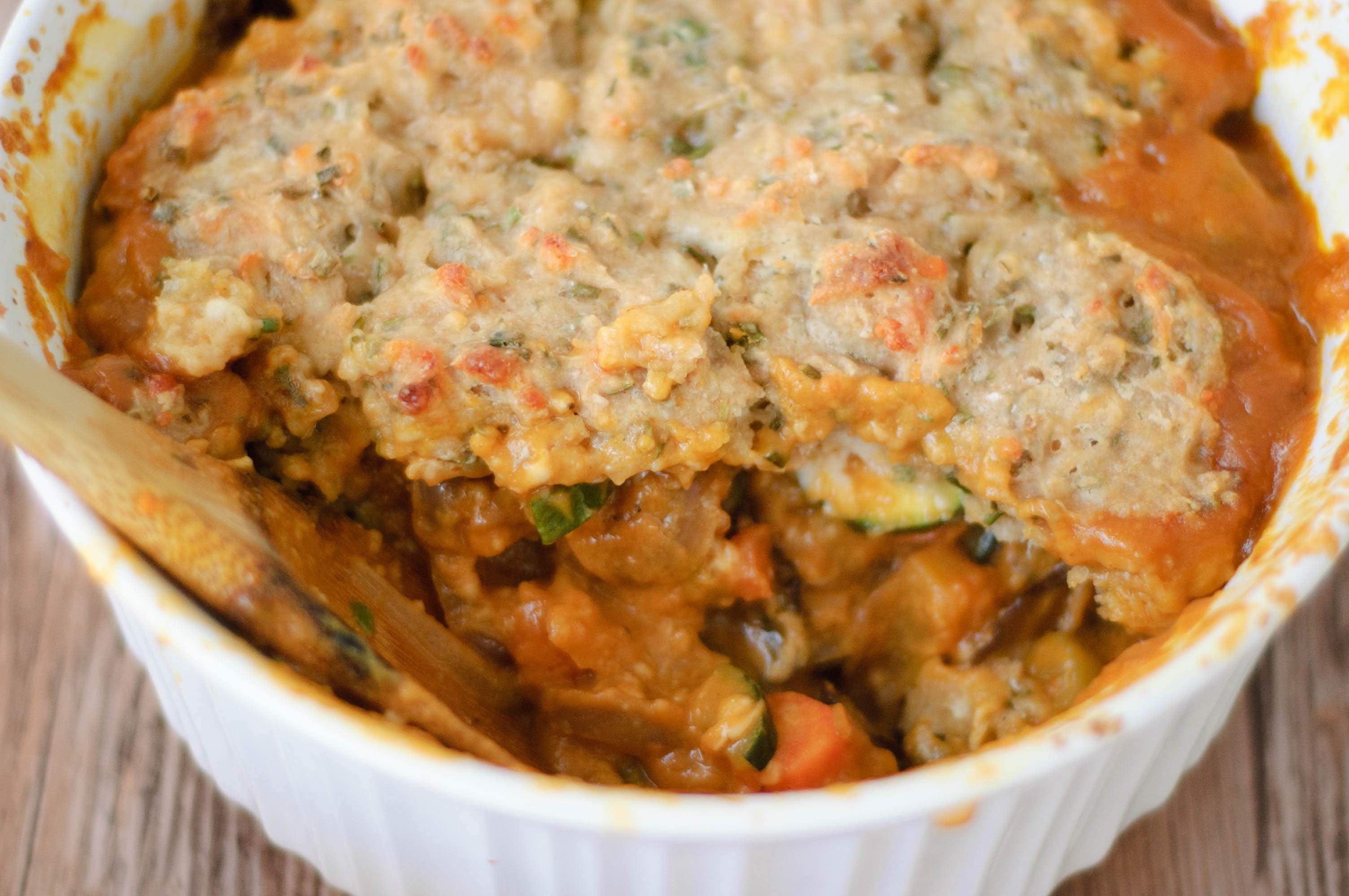 a wooden spoon dipping into a casserole dish of food.