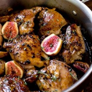 A pan of cooked chicken thighs with fresh figs.