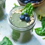 blueberries, spinach, and oats on top of a smoothie in a mason jar.