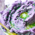 A bowl heaping with melted butter on purple mashed potatoes.