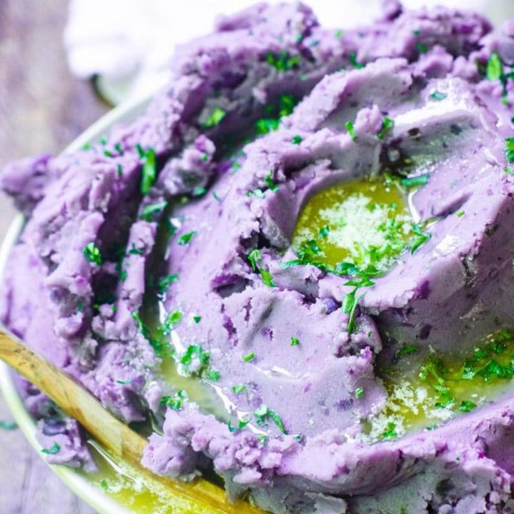 A bowl heaping with melted butter on purple mashed potatoes.