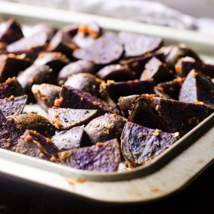 A sheet pan of cooked roasted purple potatoes.