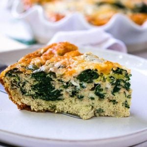 A slice of golden brown spinach egg bake on a gray plate.