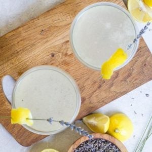 two glasses of elegant vanilla lavender cocktail on a wooden board.