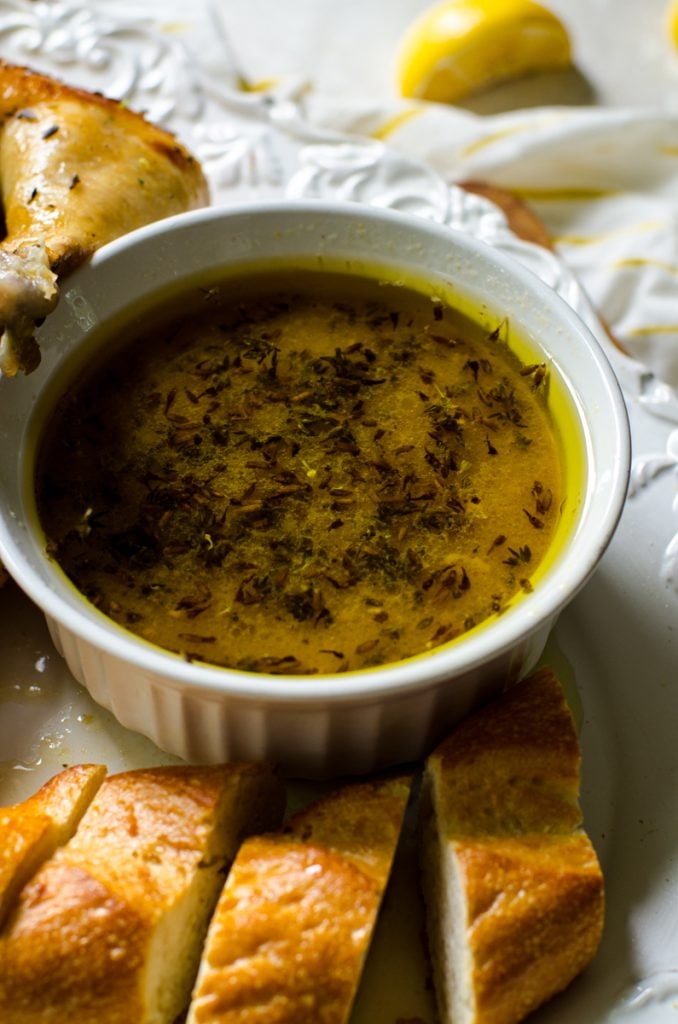 A bowl of pan juices next to sliced bread for dipping.