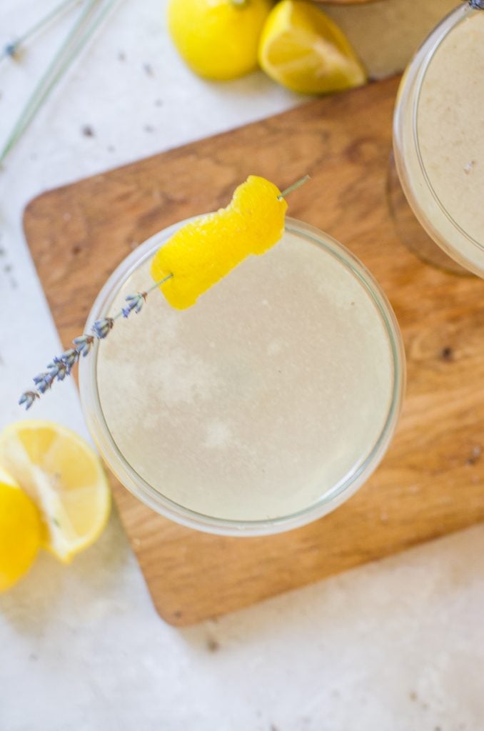 Overhead view into a lavender cocktail with a lemon and lavender garnish.