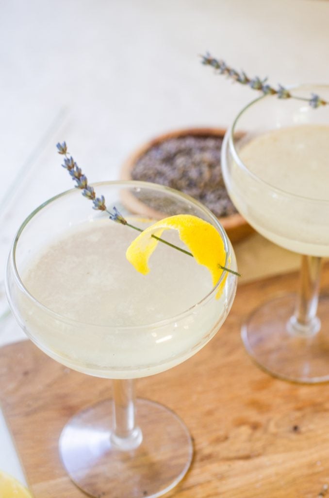 A beautiful lavender garnish on the edge of a cocktail couple glass.