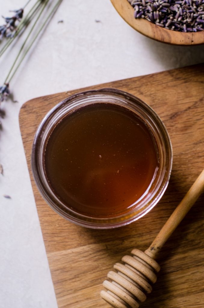 Overhead view into a mason jar of lavender honey simple syrup showing the color.