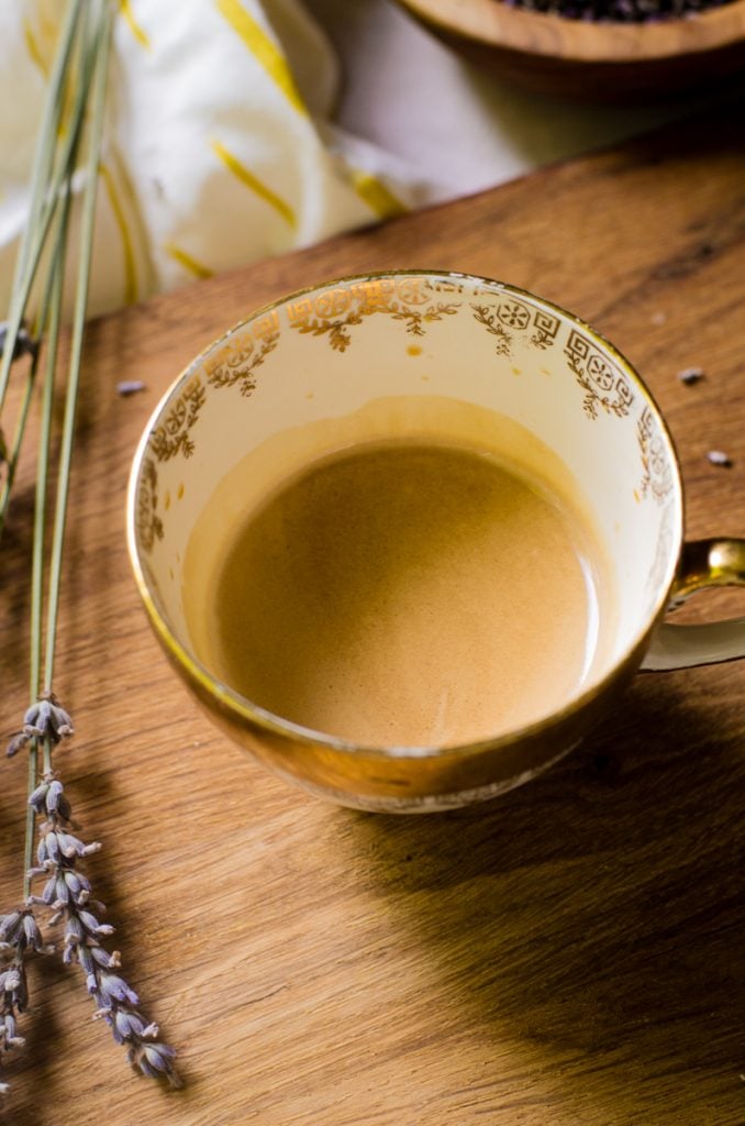 A shot of espresso in the bottom of an ornamental tea cup.