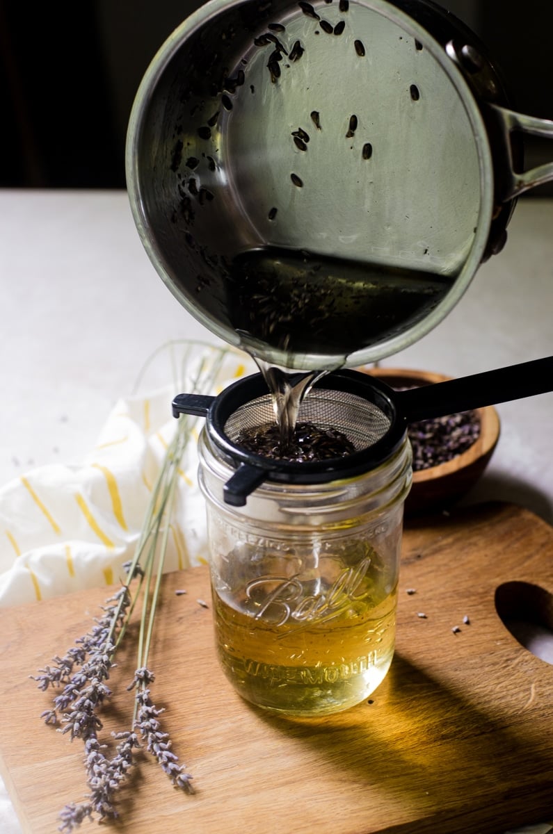 Lavender simple syrup being poured from a pot and into a mason jar.