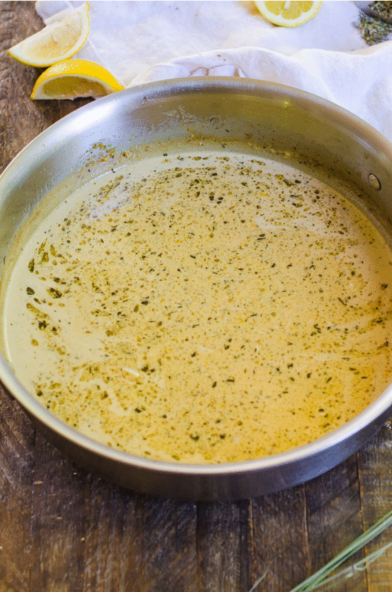 A pan swirling cold butter into a hot lemon cream sauce to make an emulsion.