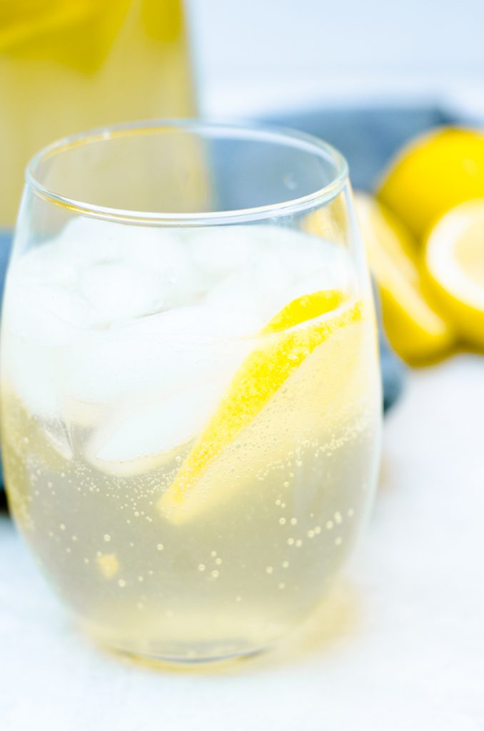 A glass of sangria garnished with a lemon slice and ice. It shows the bubbles from the Prosecco.