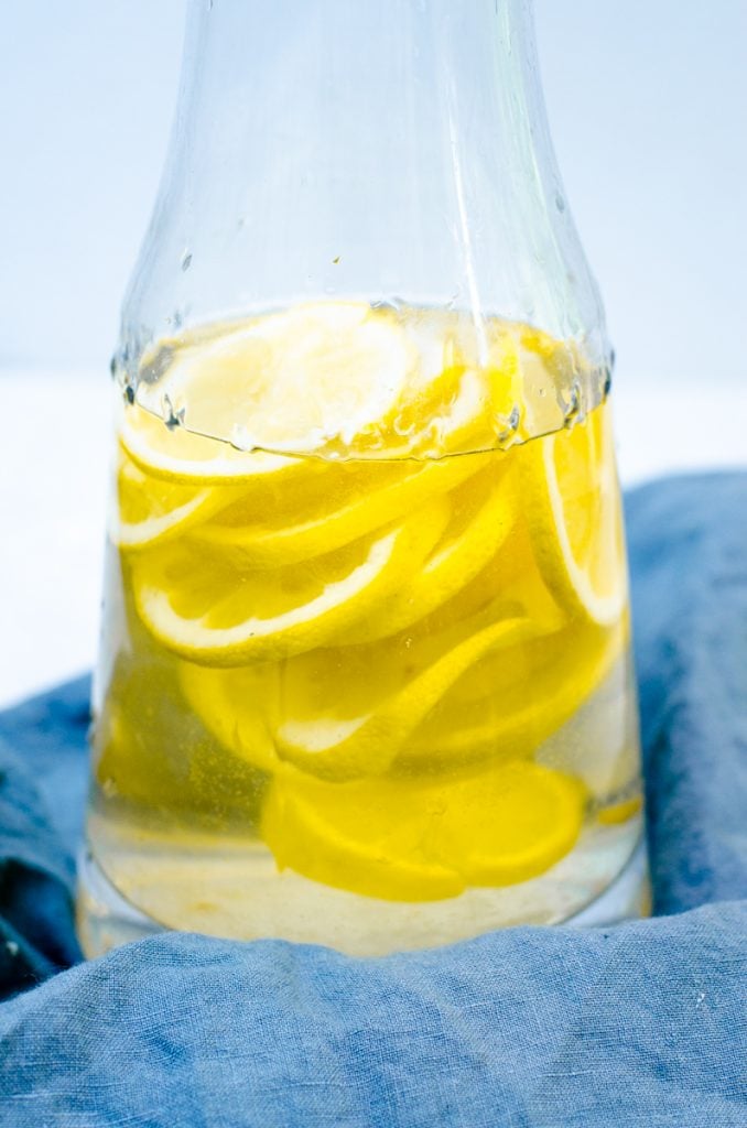 Close up of sliced lemons in white wine inside a pitcher.