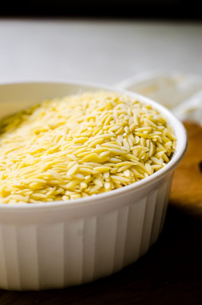 A white bowl of orzo pasta noodles.