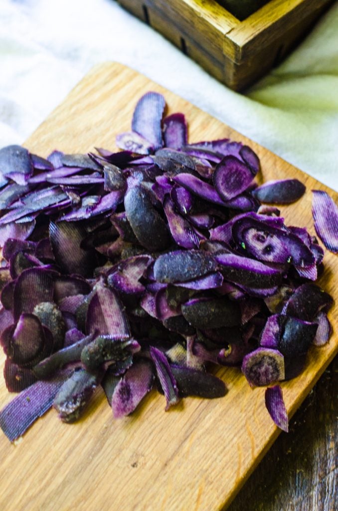 A wooden cutting board with purple potato peels