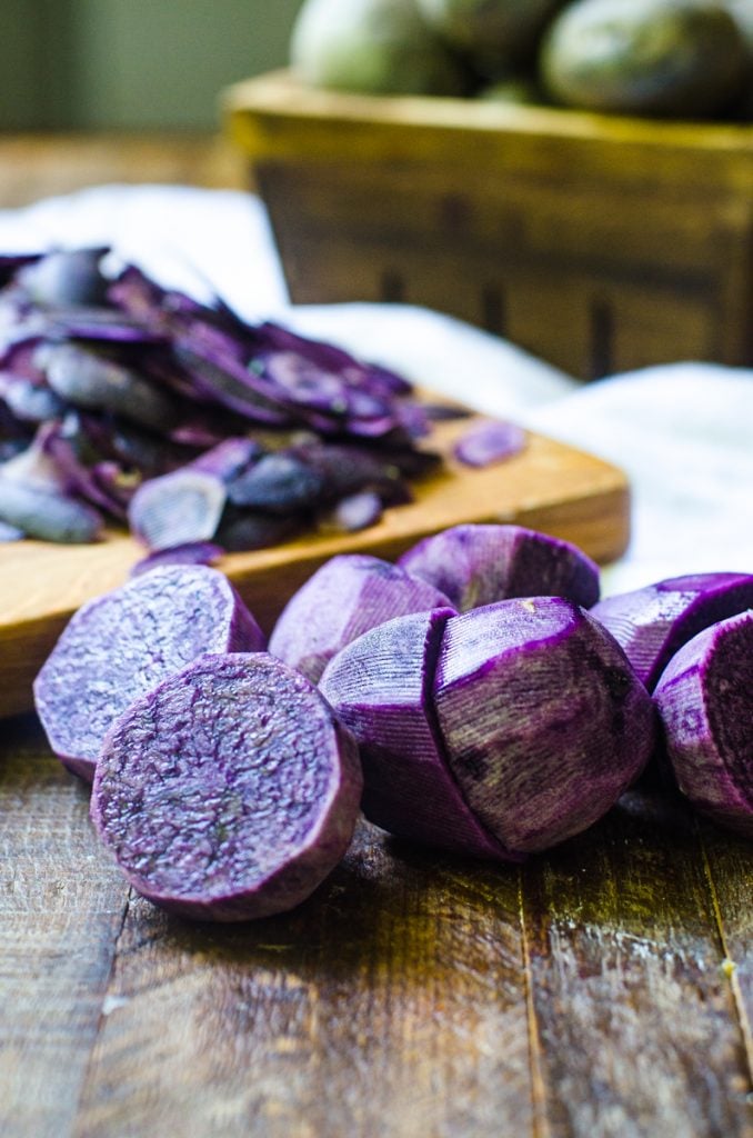 A few halves of cut and peeled purple potatoes showing the inside color.