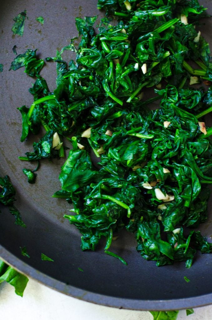 Sautéed spinach in a pan showing when it is done wilting.