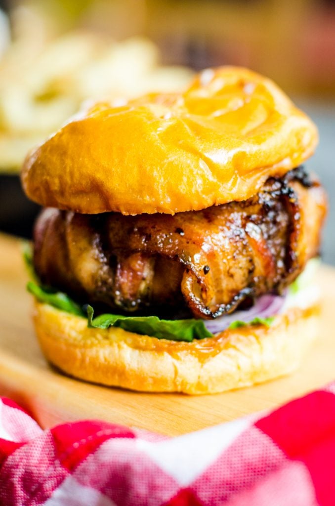 Close up of the cooked bacon on a bacon wrapped burger.