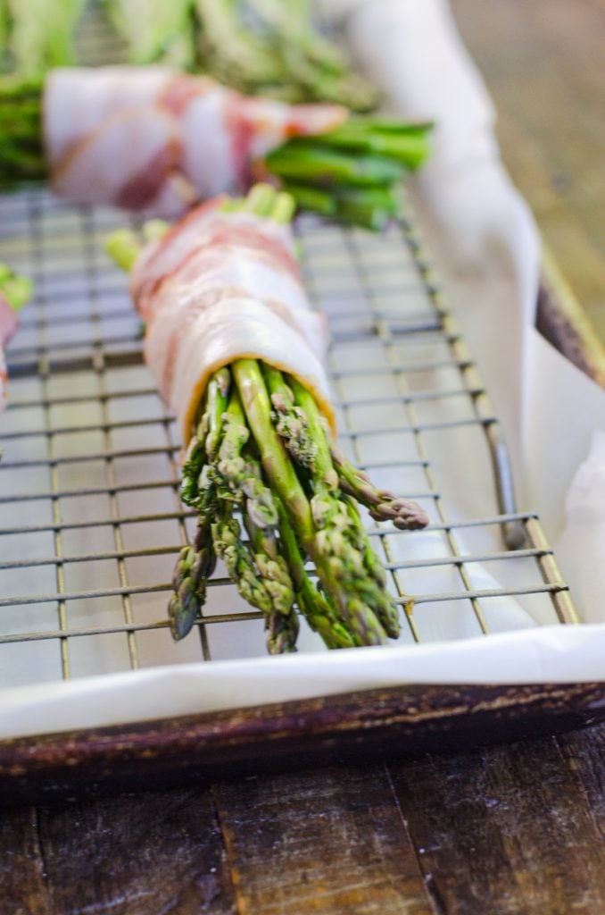 An uncooked bundle of asparagus wrapped in bacon.