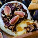 A cheese board with oozing baked brie and fig jam.
