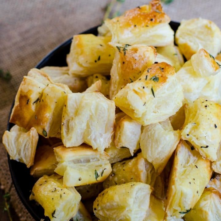 A black bowl heaping with puff pastry croutons.