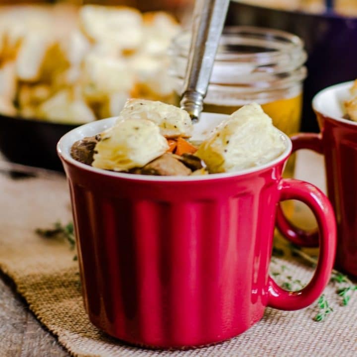 A red mug of soup with croutons and a spoon.