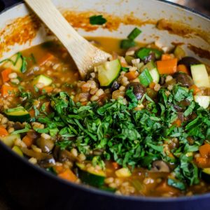 Fresh herbs garnishing a pot of soup.