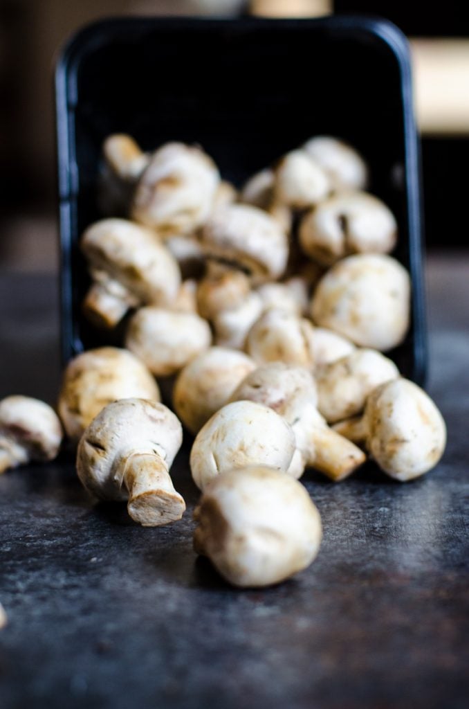 White button mushrooms spilling out of their packaging