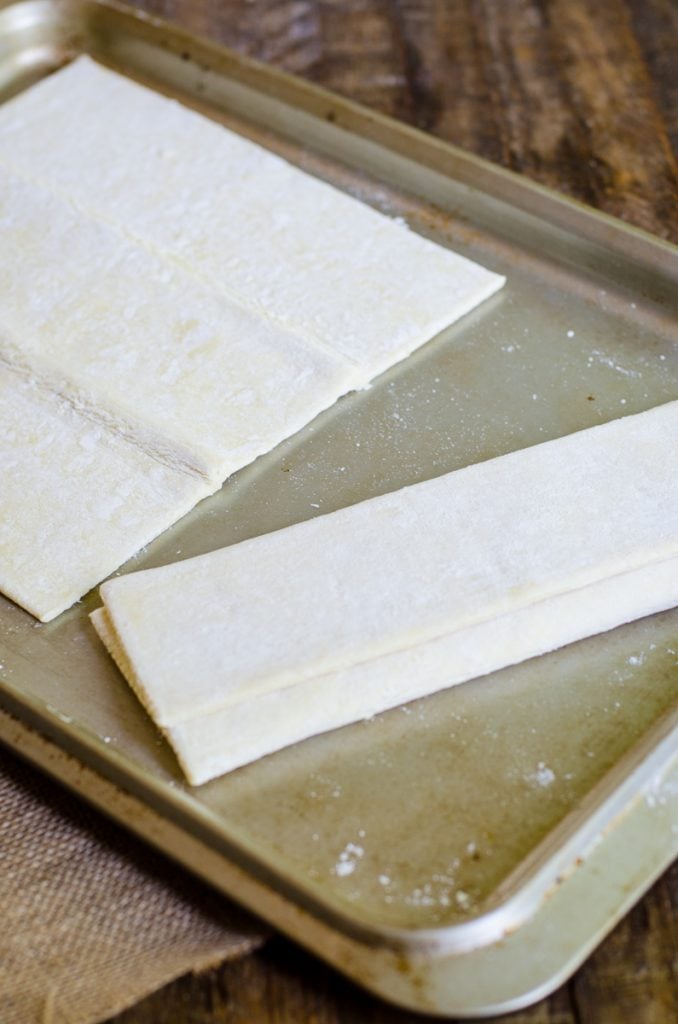 An unrolled and rolled sheet of puff pastry dough on a sheet pan.