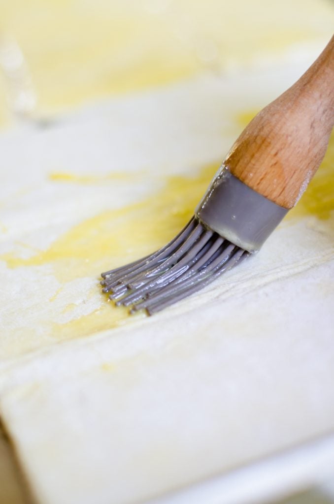 A basting brush putting egg wash on puff pastry.