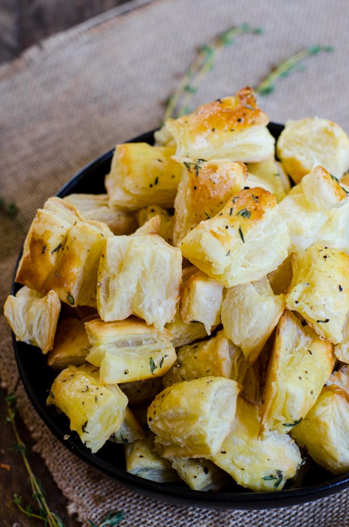 A bowl of puff pastry croutons with thyme.