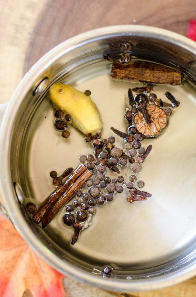 Whole spices floating in liquid in a pot.