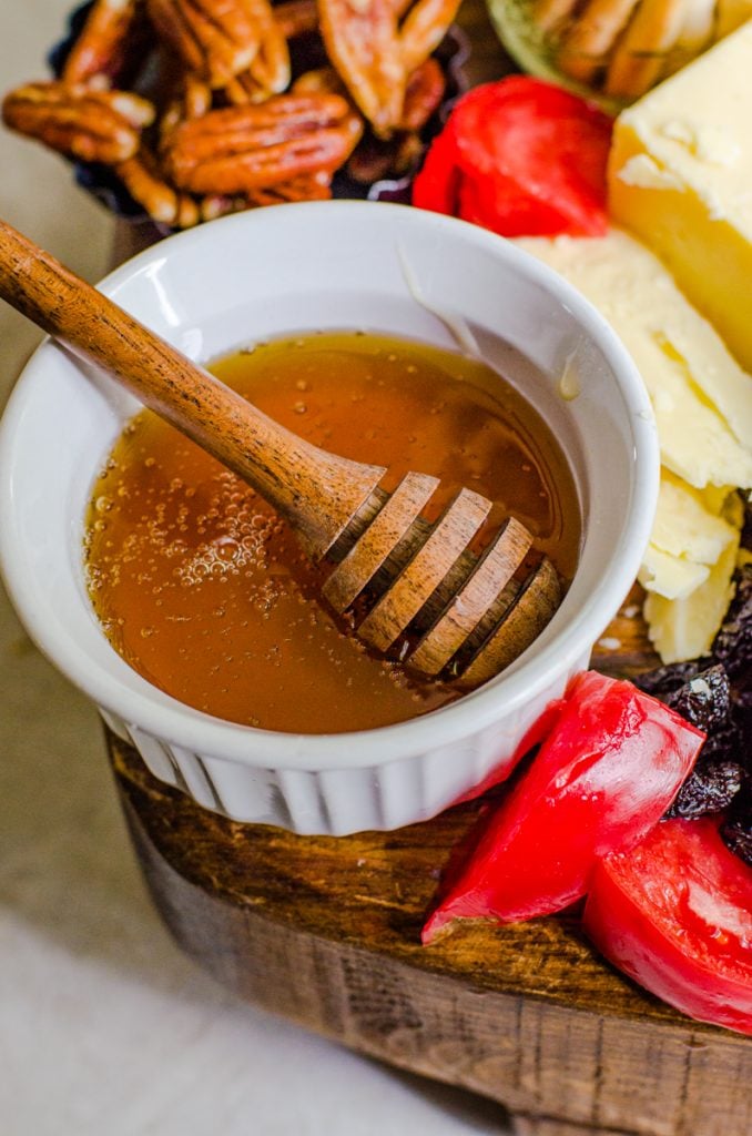 A bowl of honey with a dipper coming out of it.