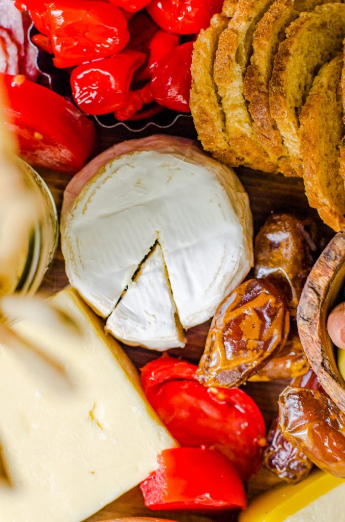 A wheel of camembert surrounded by fresh tomatoes.