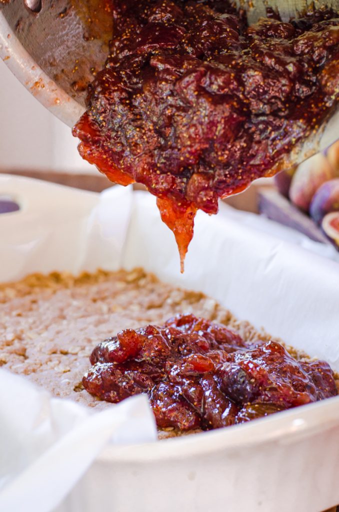 Fig jam pouring out onto prepare bar crust.