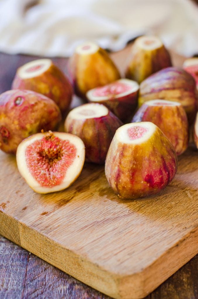 Halved and whole trimmed figs on a cutting board.