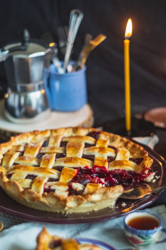 A double crust fruit pie in front of a candle.