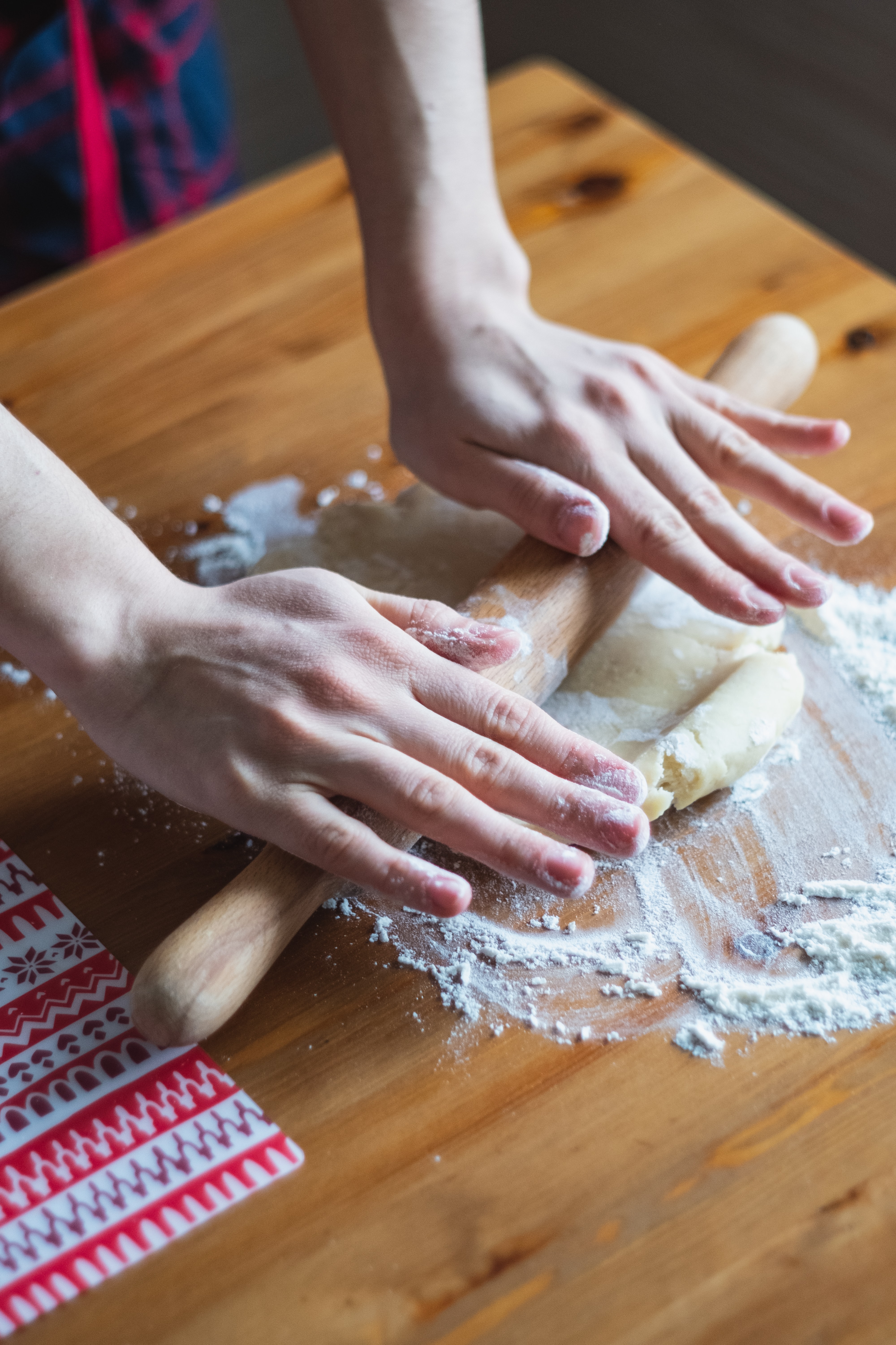 two hands using a rolling pin to roll out pie dough.