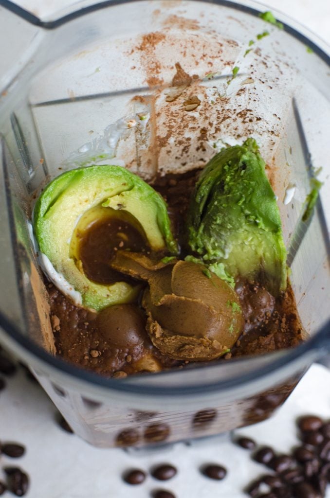 Inside of a blender filled for making a smoothie with avocado.