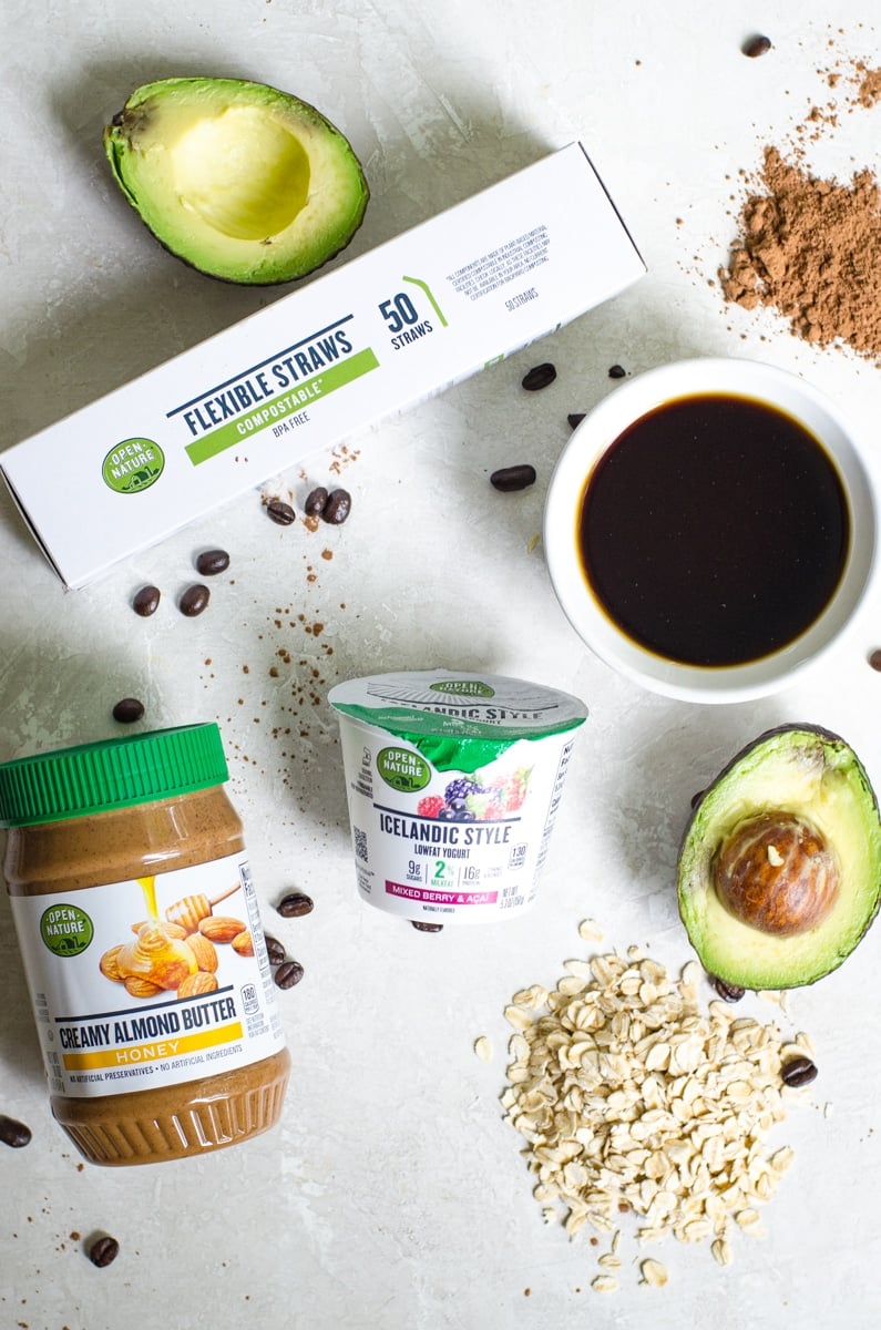 All the ingredients for a coffee smoothie laid out next to each other on a white board.