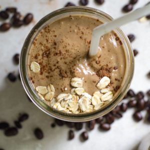 Overhead view into a mason jar of coffee smoothie with a straw.