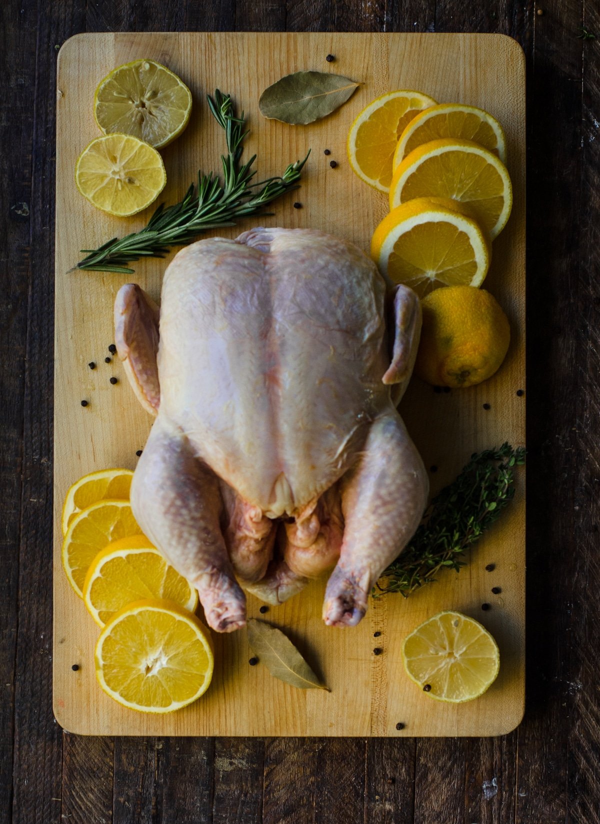 A chicken for brining on a cutting board with ingredients.