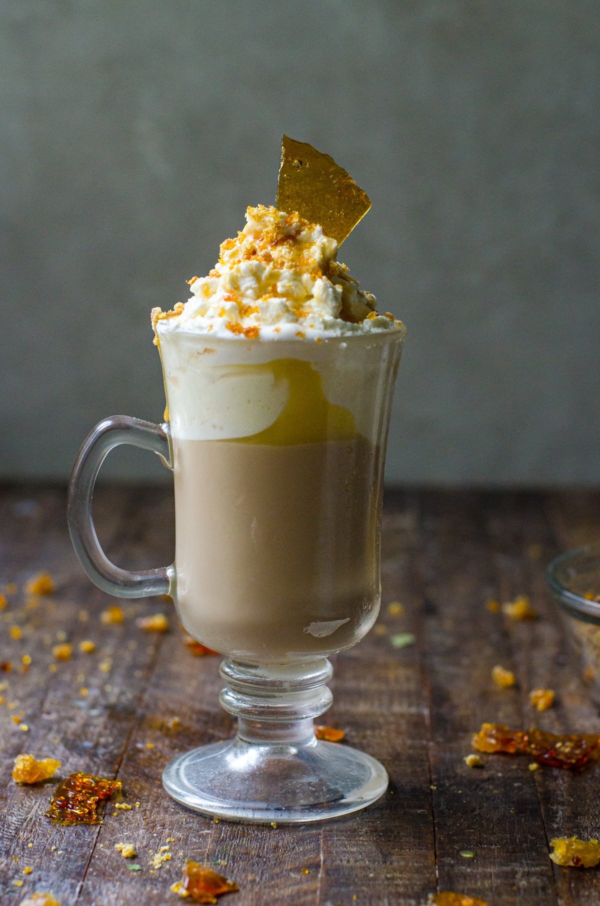 Homemade caramel brulee latte surrounded by cooked sugar pieces.